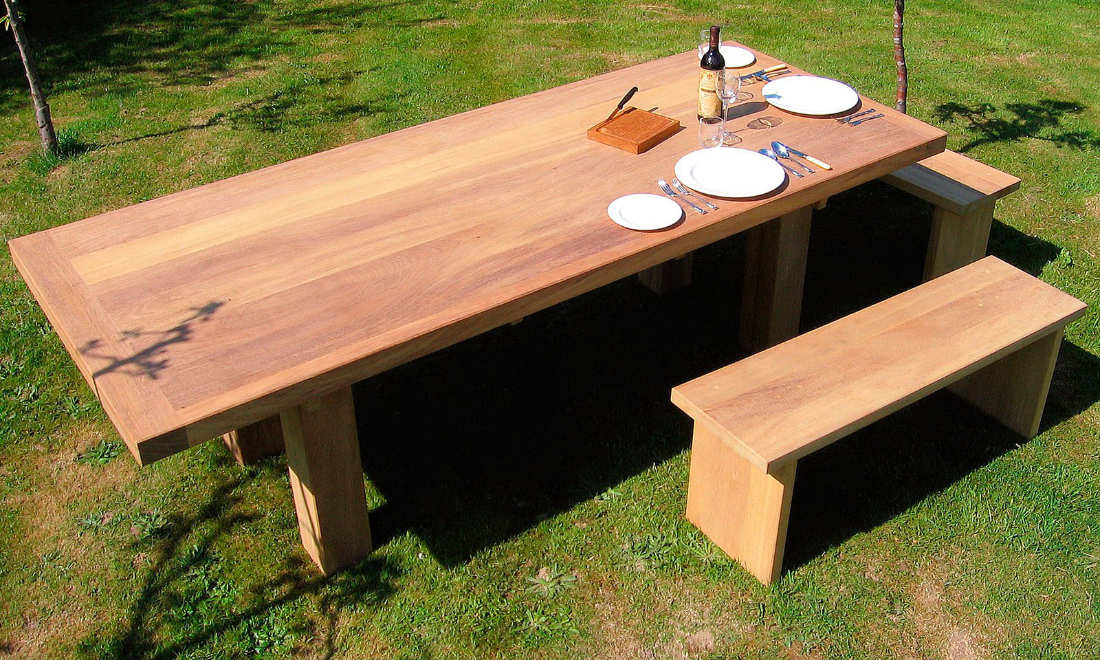 Iroko Table, with matching bench seats. A bespoke, handmade garden table manufactured out of Iroko hardwood. Quality hand-crafted exterior furniture designed and built by Mounts Hill Woodcraft.