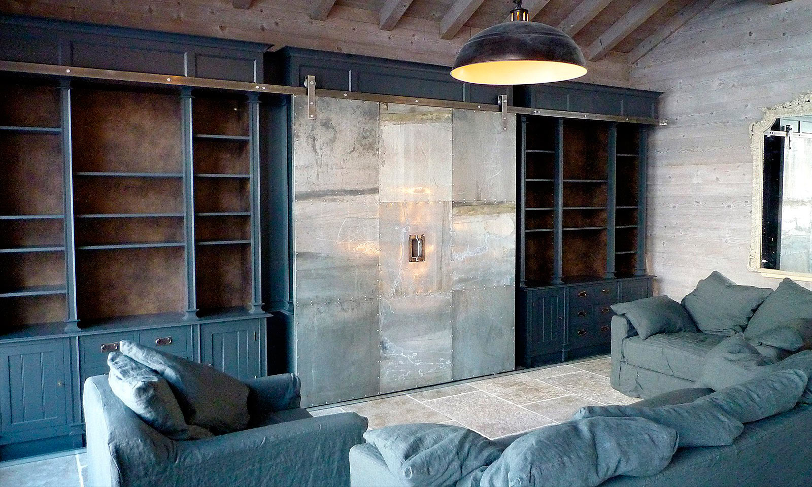 St Foy Media Unit. A bespoke and truly unique, full height media centre with an industrial twist. Manufactured for a ski chalet in St Foy, the unit features a riveted zinc sliding door and was hand-painted and installed by the skilled cabinet makers at Mounts Hill Woodcraft.
