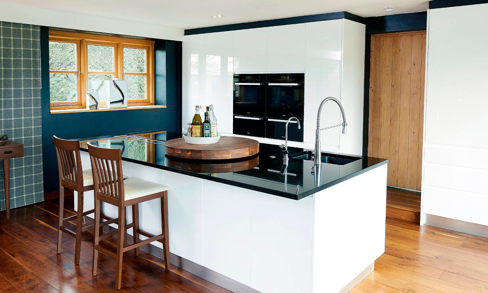 Tongswood. A bespoke, handemade, modern white kitchen, with handleless design. Made using Parapan acrylic and American walnut, a hand-crafted kitchen manufactured by the skilled cabinet makers at Mounts Hill Woodcraft.